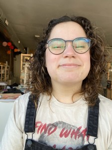 Charlie Andres, a Latin American person with curly dark hair and glasses smiling with eyes closed