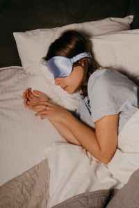 Woman sleeping in bed wearing an eye mask