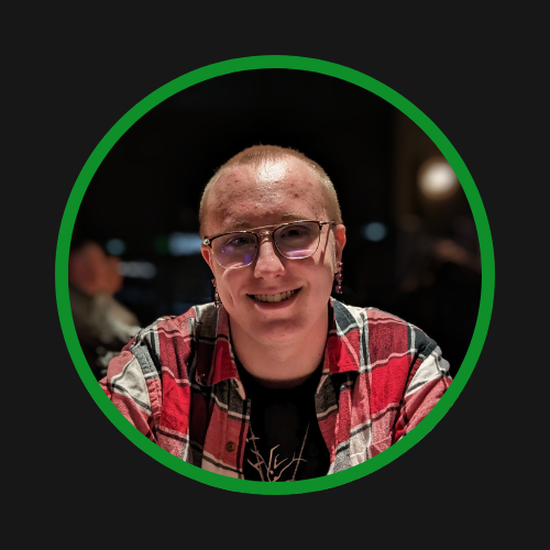 A photo of Ashton Rose wearing a red flannel shirt and glasses. The background is blurred out and there is a dark green ring around the image. 